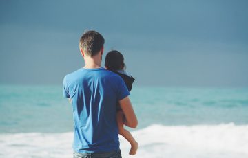 砂浜にたたずむ父と息子